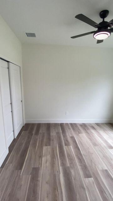 unfurnished bedroom featuring a closet, wood finished floors, visible vents, and baseboards