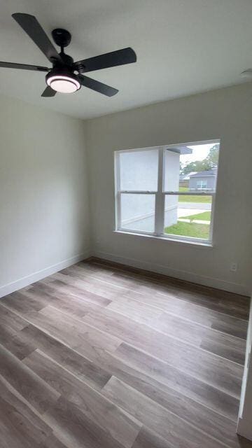 unfurnished room with ceiling fan, baseboards, and wood finished floors