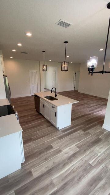 kitchen featuring light countertops, white cabinetry, a sink, and wood finished floors