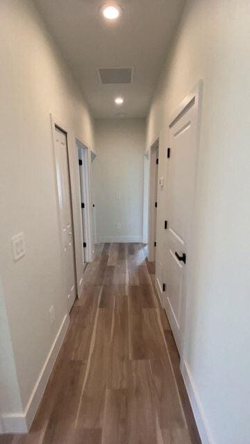 corridor featuring visible vents, baseboards, wood finished floors, and recessed lighting