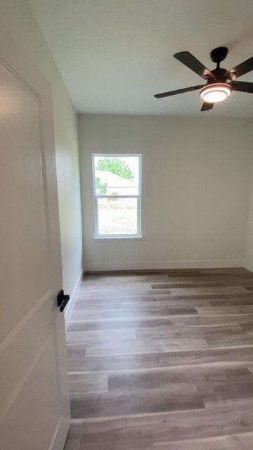 spare room featuring a ceiling fan, baseboards, and light wood finished floors