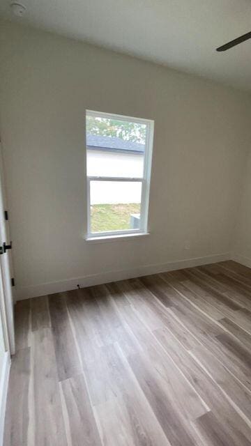 spare room featuring wood finished floors, a ceiling fan, and baseboards