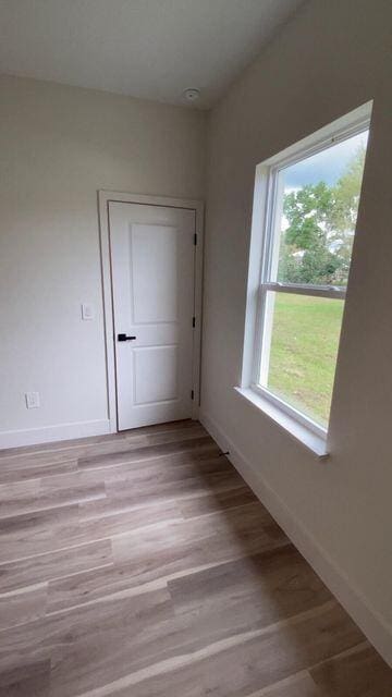 empty room featuring light wood-type flooring and baseboards