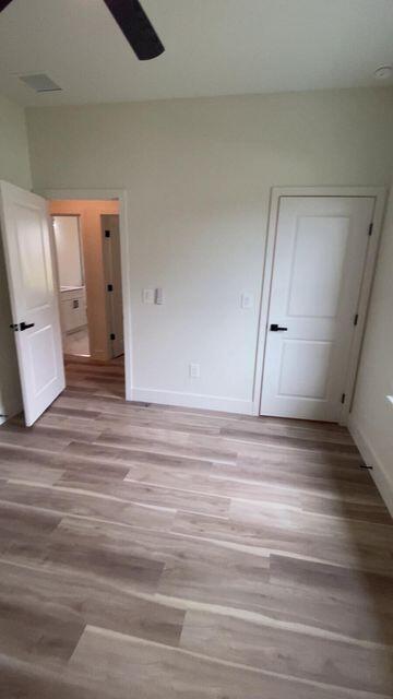 unfurnished bedroom with ceiling fan, light wood finished floors, and baseboards