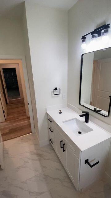 bathroom with marble finish floor, vanity, and baseboards