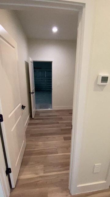 hallway featuring light wood-style flooring and baseboards