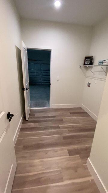 clothes washing area with baseboards and wood finished floors