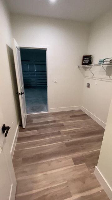 clothes washing area with wood finished floors and baseboards