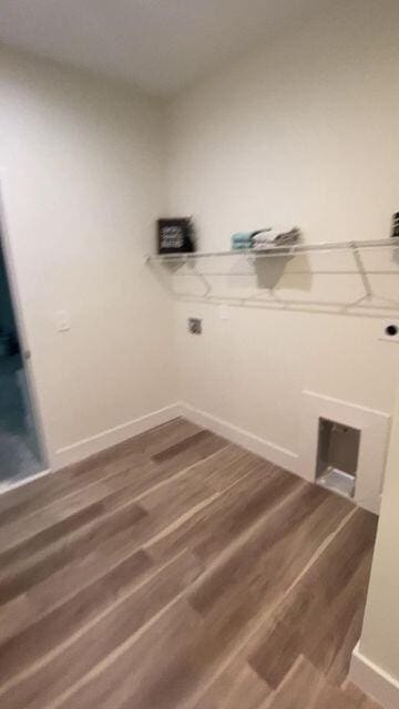 clothes washing area with laundry area, wood finished floors, and baseboards