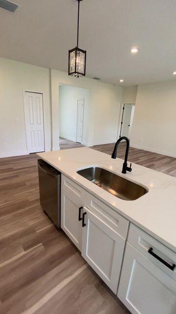 kitchen with visible vents, white cabinets, dishwasher, dark wood-type flooring, and a sink