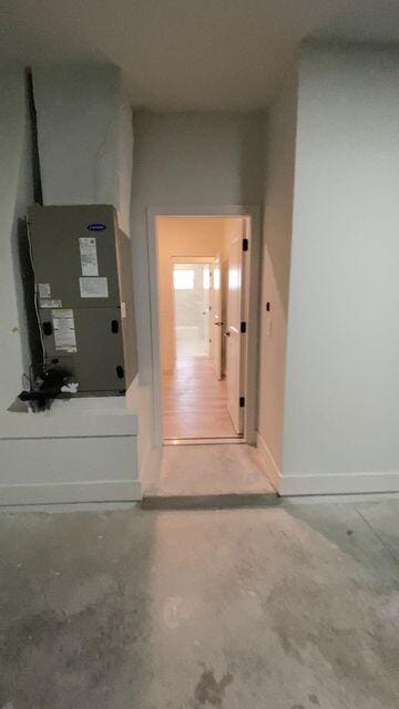 hallway with concrete floors, heating unit, and baseboards