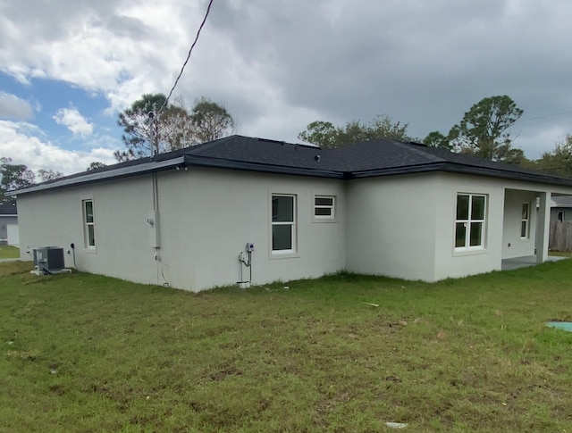 back of house featuring a yard, central AC unit, and stucco siding