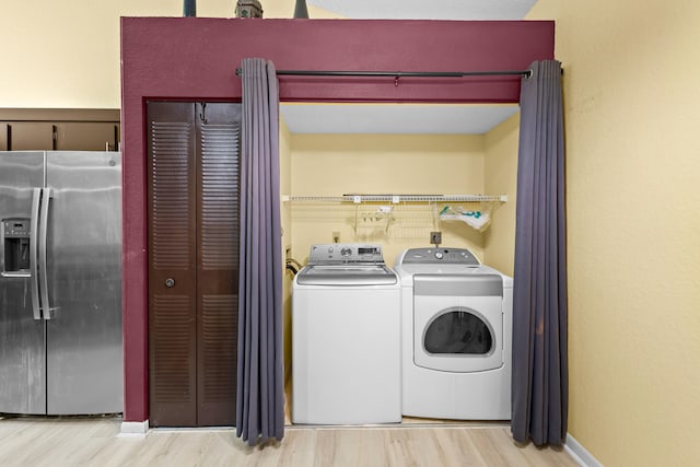 clothes washing area with laundry area, baseboards, separate washer and dryer, and wood finished floors