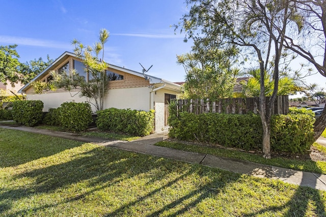 view of front of house with stucco siding, fence, and a front yard