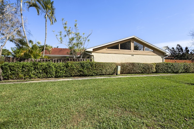 exterior space with a lawn, fence, and stucco siding