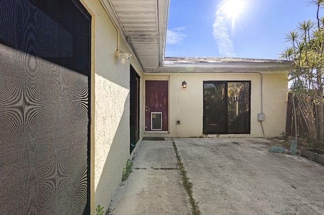 entrance to property featuring a patio area and stucco siding