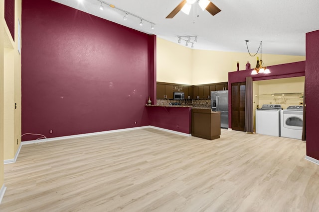 kitchen with ceiling fan with notable chandelier, a peninsula, appliances with stainless steel finishes, light wood-type flooring, and washer and clothes dryer