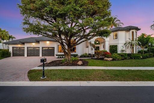 view of front of property featuring a garage, a yard, driveway, and stucco siding