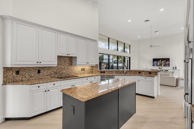 kitchen with stone counters, tasteful backsplash, a peninsula, and white cabinetry