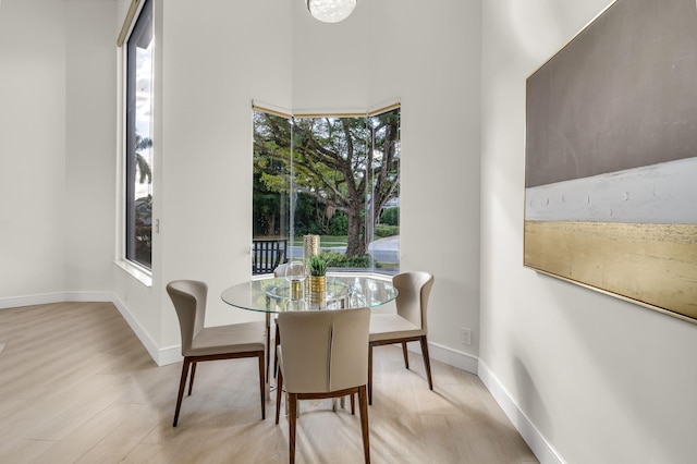 dining space featuring light wood-type flooring and baseboards