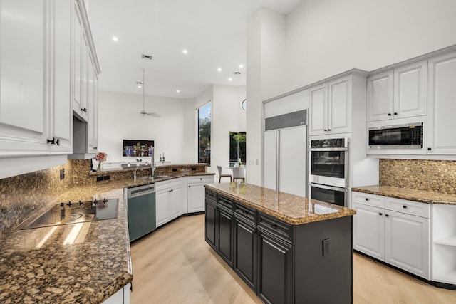 kitchen featuring built in appliances, dark stone countertops, a center island, and decorative backsplash