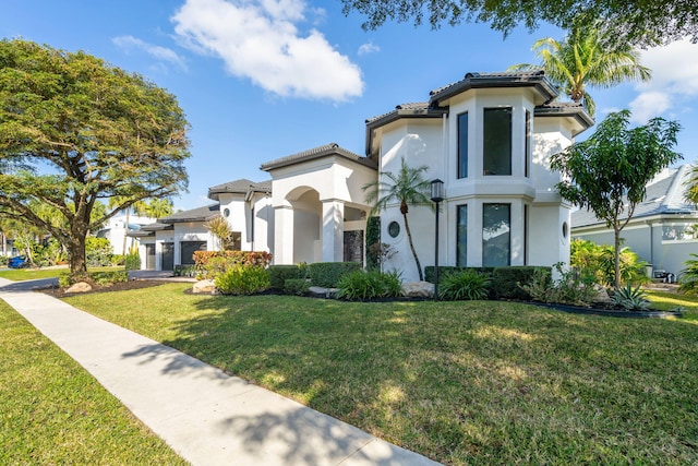 mediterranean / spanish house with stucco siding, a tiled roof, and a front yard