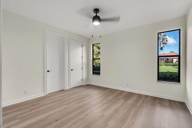 unfurnished bedroom with baseboards, light wood-style floors, and multiple closets