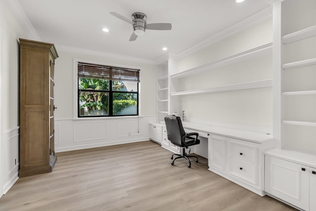 office space with ornamental molding, built in features, built in desk, light wood finished floors, and ceiling fan