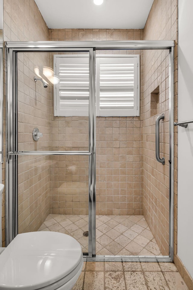 bathroom featuring toilet and a stall shower
