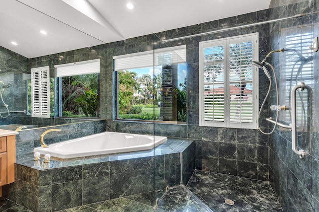 bathroom with vanity, a garden tub, vaulted ceiling, tiled shower, and tile walls