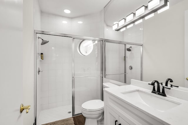 full bathroom featuring a shower stall, toilet, and vanity