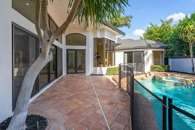 view of patio featuring french doors, fence, and a pool with connected hot tub