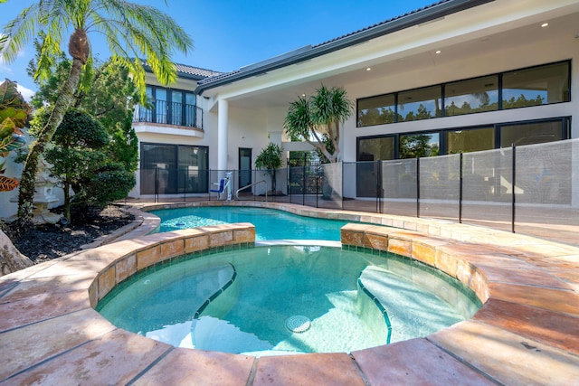 view of pool with a pool with connected hot tub and fence