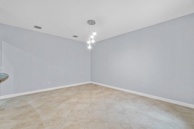 unfurnished room with baseboards and visible vents