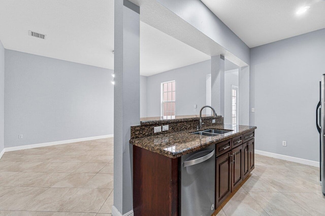 kitchen featuring visible vents, stainless steel dishwasher, a sink, dark stone countertops, and dark brown cabinets