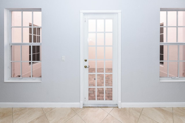 doorway with plenty of natural light, baseboards, and tile patterned floors