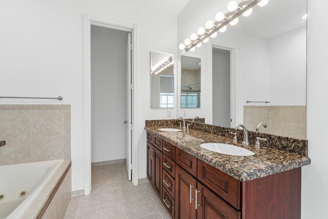 bathroom with double vanity, a tub with jets, a sink, and tile patterned floors