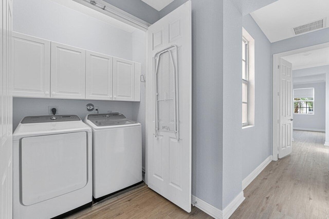 laundry room with washing machine and dryer, light wood-style flooring, visible vents, baseboards, and cabinet space
