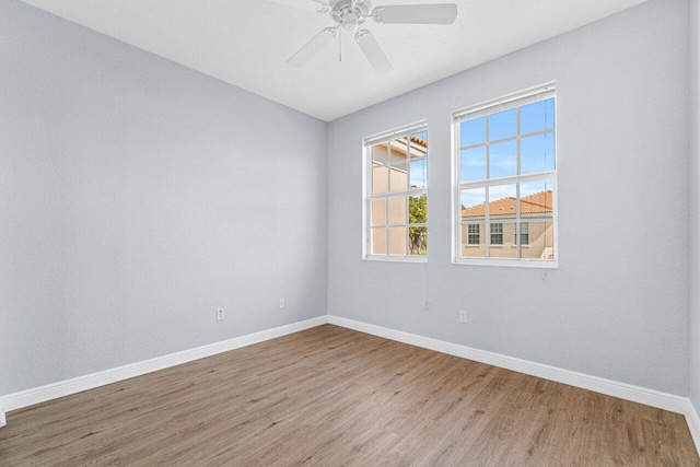 empty room with ceiling fan, wood finished floors, and baseboards