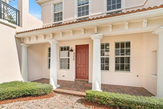 view of exterior entry featuring a porch and stucco siding