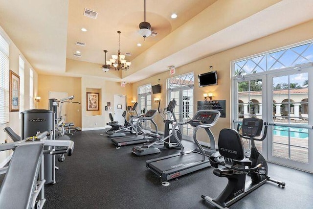 gym featuring visible vents, baseboards, a raised ceiling, a chandelier, and recessed lighting
