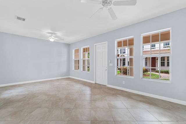 tiled empty room with visible vents, ceiling fan, and baseboards