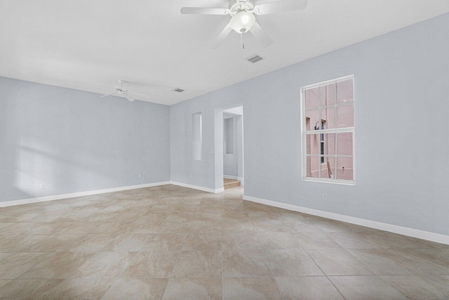 unfurnished room with a ceiling fan, visible vents, and baseboards