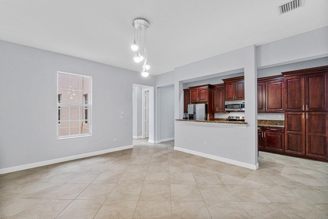 kitchen with reddish brown cabinets, visible vents, baseboards, stainless steel microwave, and fridge with ice dispenser