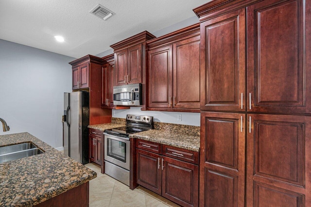 kitchen featuring light tile patterned floors, stainless steel appliances, a sink, visible vents, and dark brown cabinets