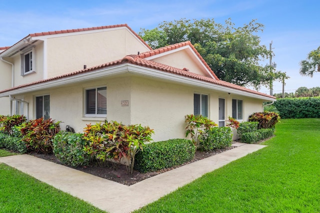 6320 Walk Cir Unit 17, Boca Raton, FL 33433 - view of home's exterior featuring a yard, a tiled roof, and stucco siding