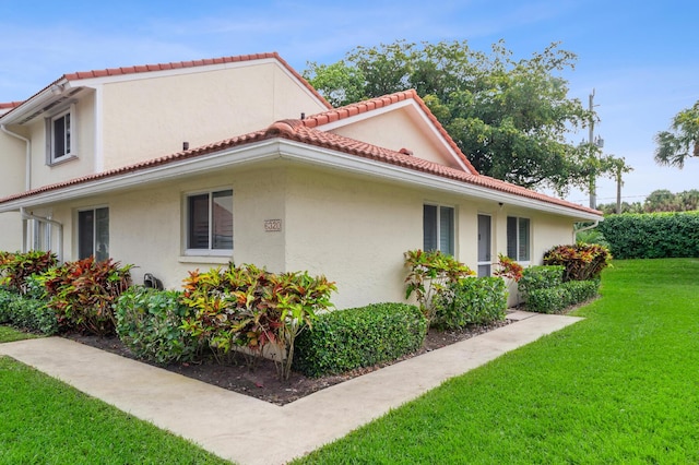 view of home's exterior featuring a yard, a tiled roof, and stucco siding