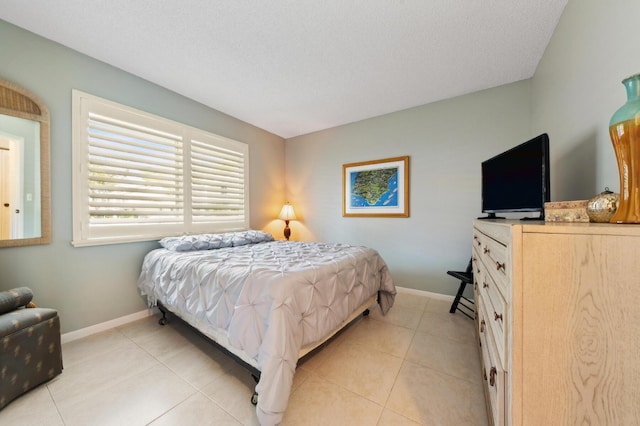 bedroom with a textured ceiling, light tile patterned flooring, and baseboards