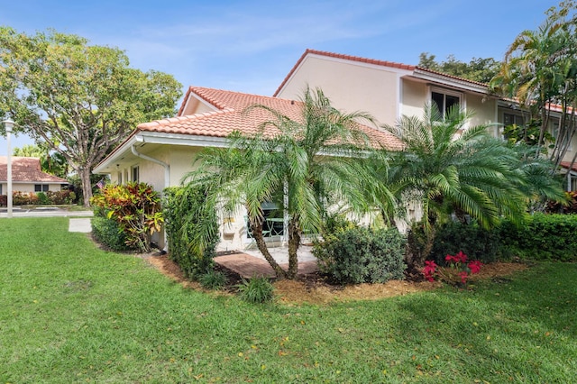 view of side of home featuring a tile roof, a lawn, and stucco siding