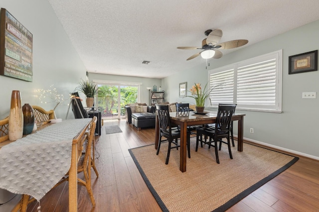 dining area featuring a ceiling fan, wood-type flooring, baseboards, and a textured ceiling